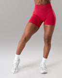 Person wearing red athletic shorts and white sneakers on a gray background